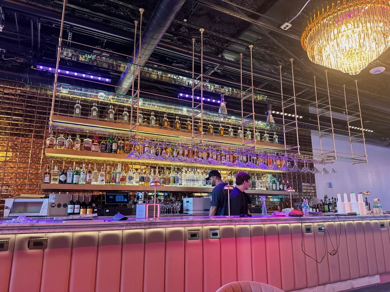 Ceiling-mounted brass bar shelving in an industrial loft space, unlacquered brass finish, BrassShelf