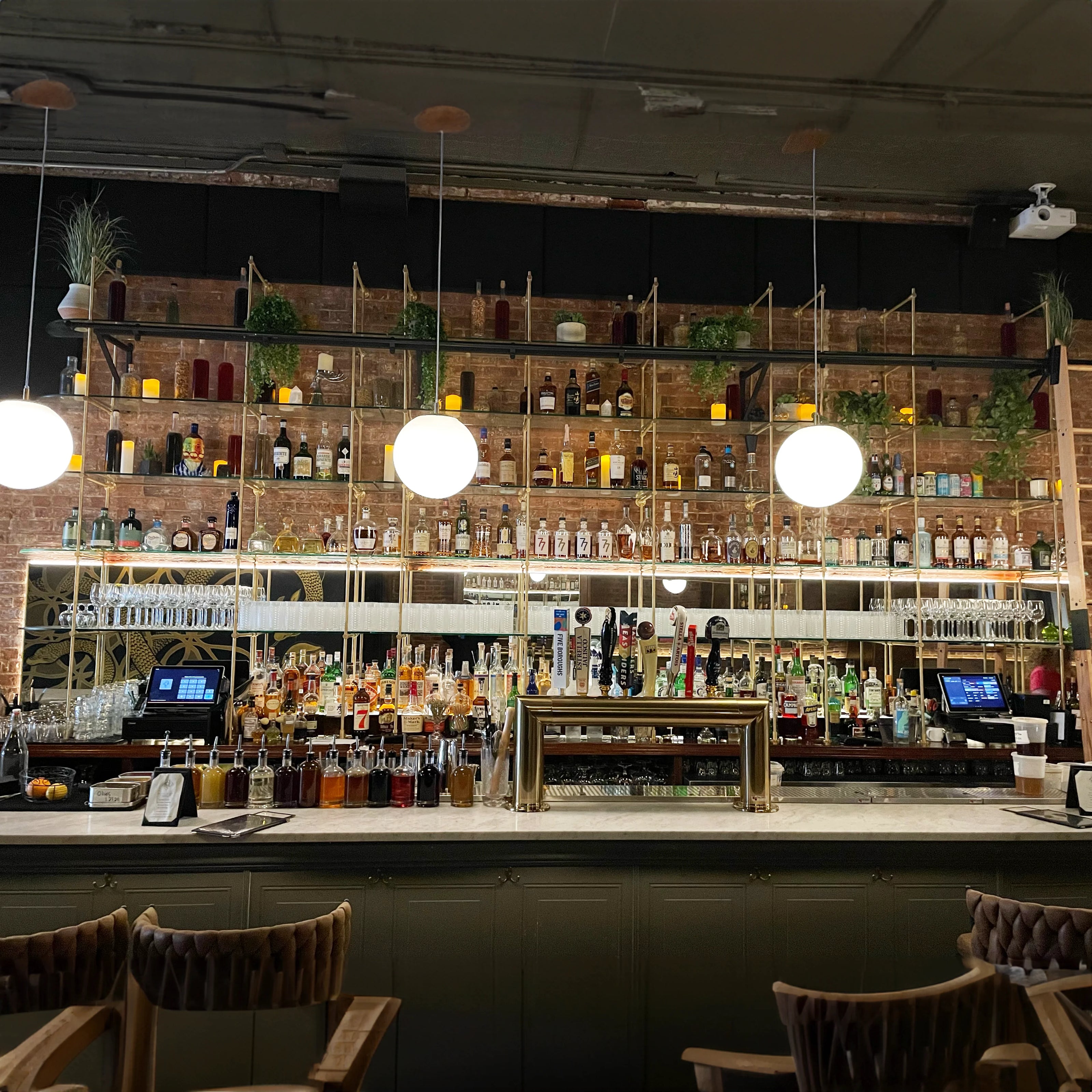 Full-wall brass shelving system for a restaurant bar — custom made by BrassShelf
